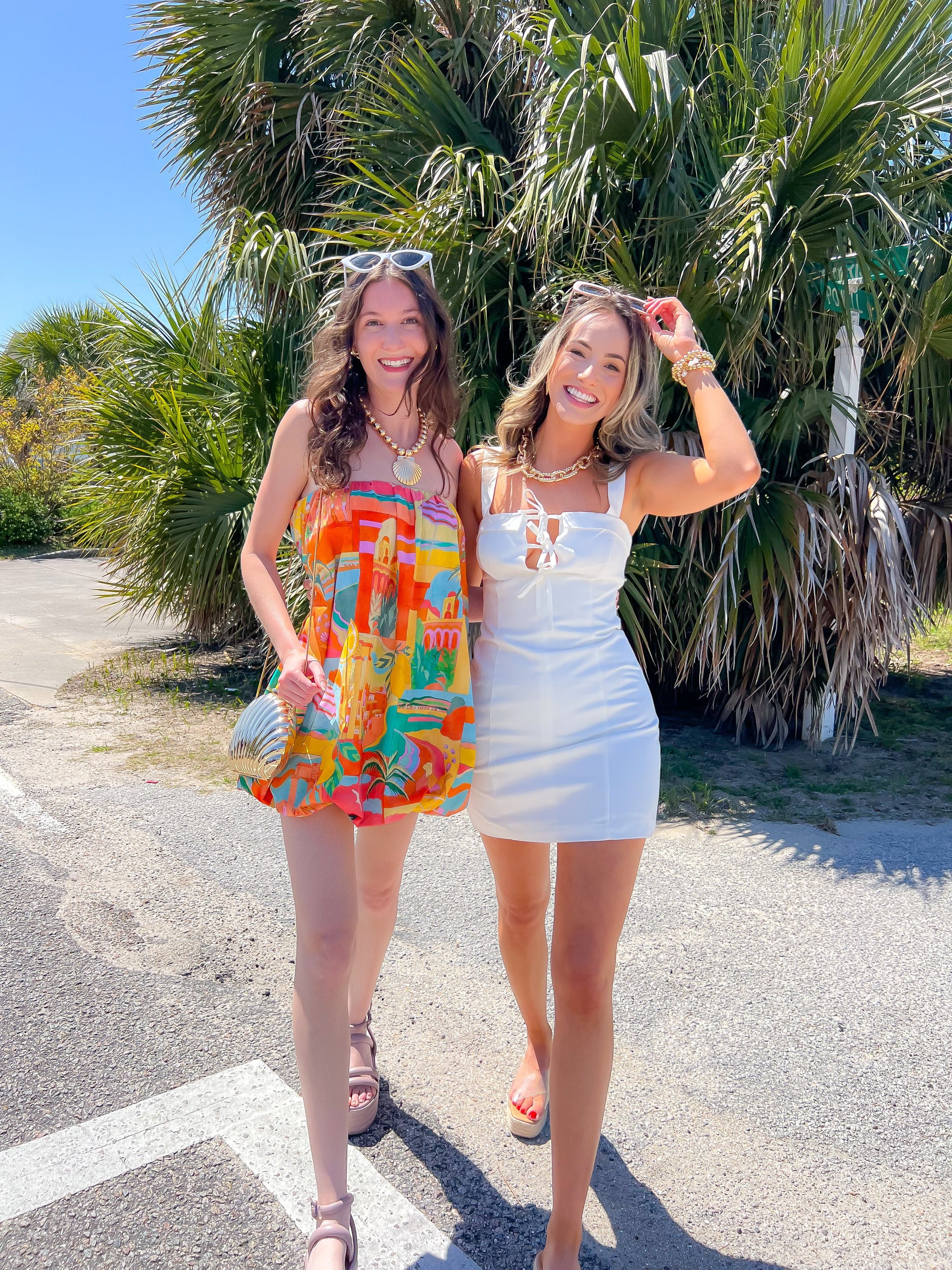 Stylish women in vibrant Miss Malibu vacation dresses under palm trees.