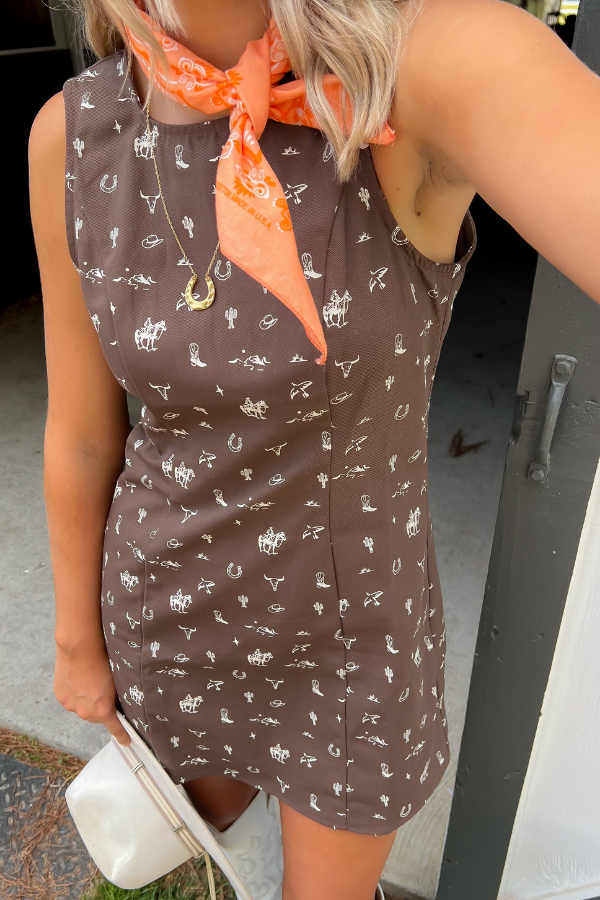 Close-up of Giddy Up Brown Cowboy Print Mini Dress showing western-themed white print and sleeveless design, ideal for casual western wear.