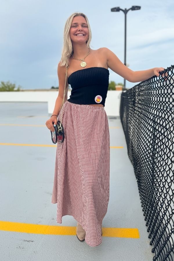 Crimson gingham maxi skirt with elastic waist, paired with a black top and boots, ideal for fall gameday or Thanksgiving outfits.