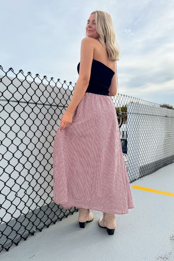 Side-back angle of the crimson gingham maxi skirt styled for fall, showcasing its flattering fit and casual elegance for gameday wear.