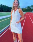 Ellie Beige Halter Neck Scalloped Mini Dress with front buttons and pockets, styled for game day with boots on a track field.