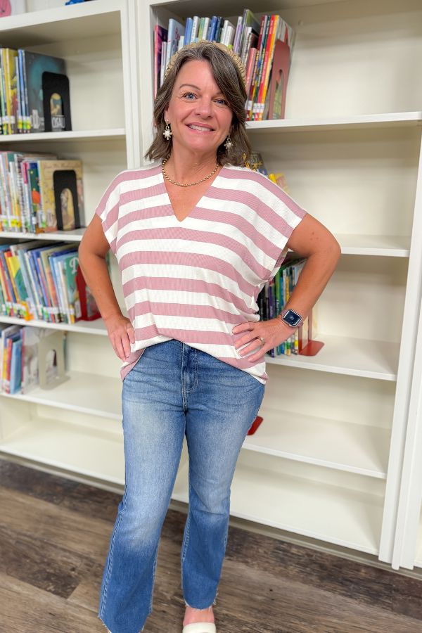 Mauve V-Neck Striped Top with blush and white horizontal stripes, styled with jeans for a casual summer look in a library setting.