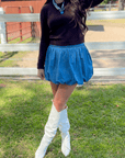 Denim Bubble Skort - Mini Skort styled with white boots and black top, featuring high waist and bubble hem for a chic fall look.