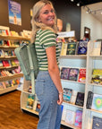 Back view of Green Stripe Knit Top WM paired with denim and a sage green backpack, showcasing the tee's collegiate-inspired design.