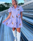 Lavender Sequin Football Dress - Trendsetting Gameday Style with sequin football patches, puff sleeves, and tiered ruffle skirt, styled with white boots.