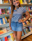 Easy A Blue Striped Baby Tee – Cropped & Campus-Ready top with button v-neck, styled with a denim mini skirt in a bookstore setting.