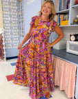 Purple Leaf Maxi Dress - Multicolor Print with flowy fit and ruffle sleeves, styled for back to school in a classroom setting.