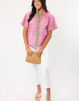 THML Pink Floral Smocked Neck Top with green trim and flutter sleeves, styled with white cropped pants and nude platform sandals. A stylish spring essential for casual or dressy looks.