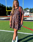 Model wearing Tiger Printed Button Down Mini Dress – Gameday Shirt Dress with a stadium backdrop, showcasing its relaxed fit and playful print.