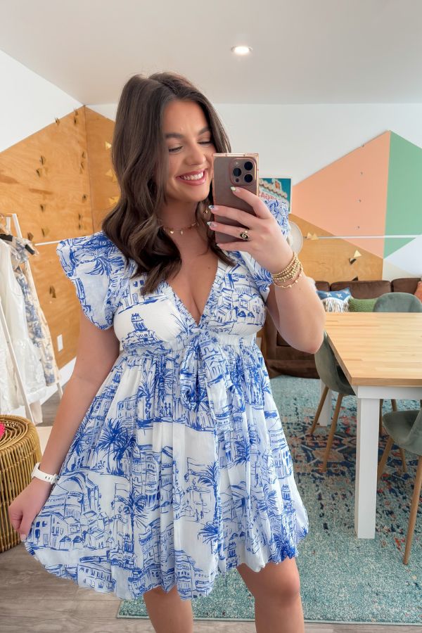 Meet Me in Santorini Coastal Sketch Dress in blue and white Mediterranean print, shown in a casual indoor setting with mirror selfie.