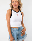 Cherry On Top Halter Neck Tank featuring a white ribbed fabric with black contrast trim and an embroidered cherry design. A cute summer essential styled with denim shorts.