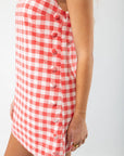 Close-up of Poppy Red Gingham Mini Dress side button detail, showcasing its playful pattern and tailored fit for casual summer wear.