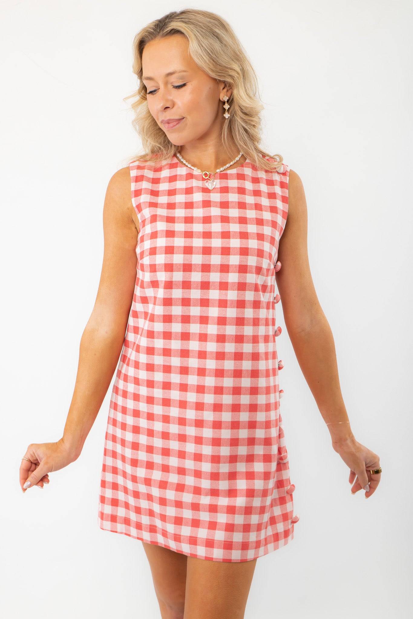 Front view of Poppy Red Gingham Mini Dress with side buttons, highlighting its vibrant checkered pattern and relaxed summer style.