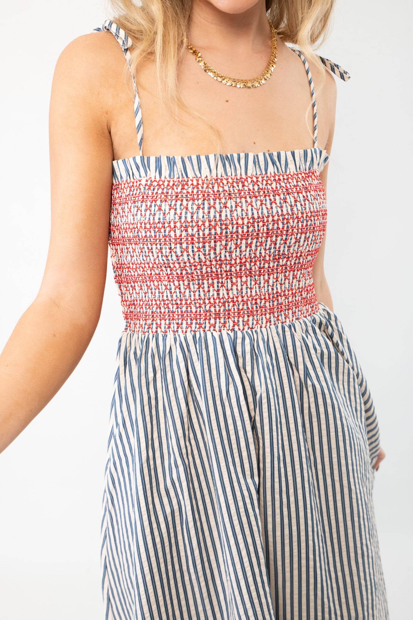 Close-up of THML Smocked Blue Striped Tie Strap Midi Dress showing red smocked bodice and blue vertical stripes, perfect for casual summer wear.