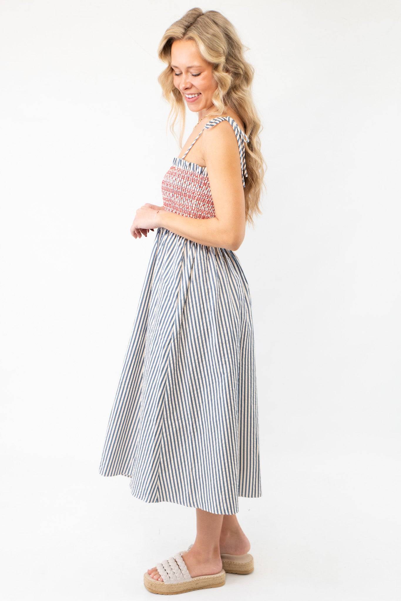 Side view of THML Smocked Blue Striped Tie Strap Midi Dress with tie straps and flared skirt, a stylish choice for vacation or Fourth of July events.