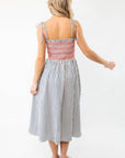 Back view of THML Smocked Blue Striped Tie Strap Midi Dress with red smocked top and striped skirt, a chic and comfortable summer dress option.