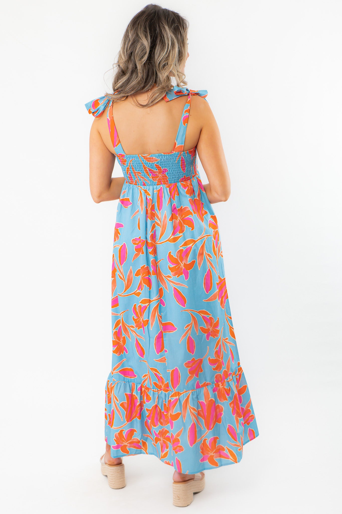 Rear full-length view of THML Tie Strap Flower Print Maxi Dress with ruffled hem and colorful floral design, ideal for beach vacations.