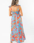 Rear full-length view of THML Tie Strap Flower Print Maxi Dress with ruffled hem and colorful floral design, ideal for beach vacations.