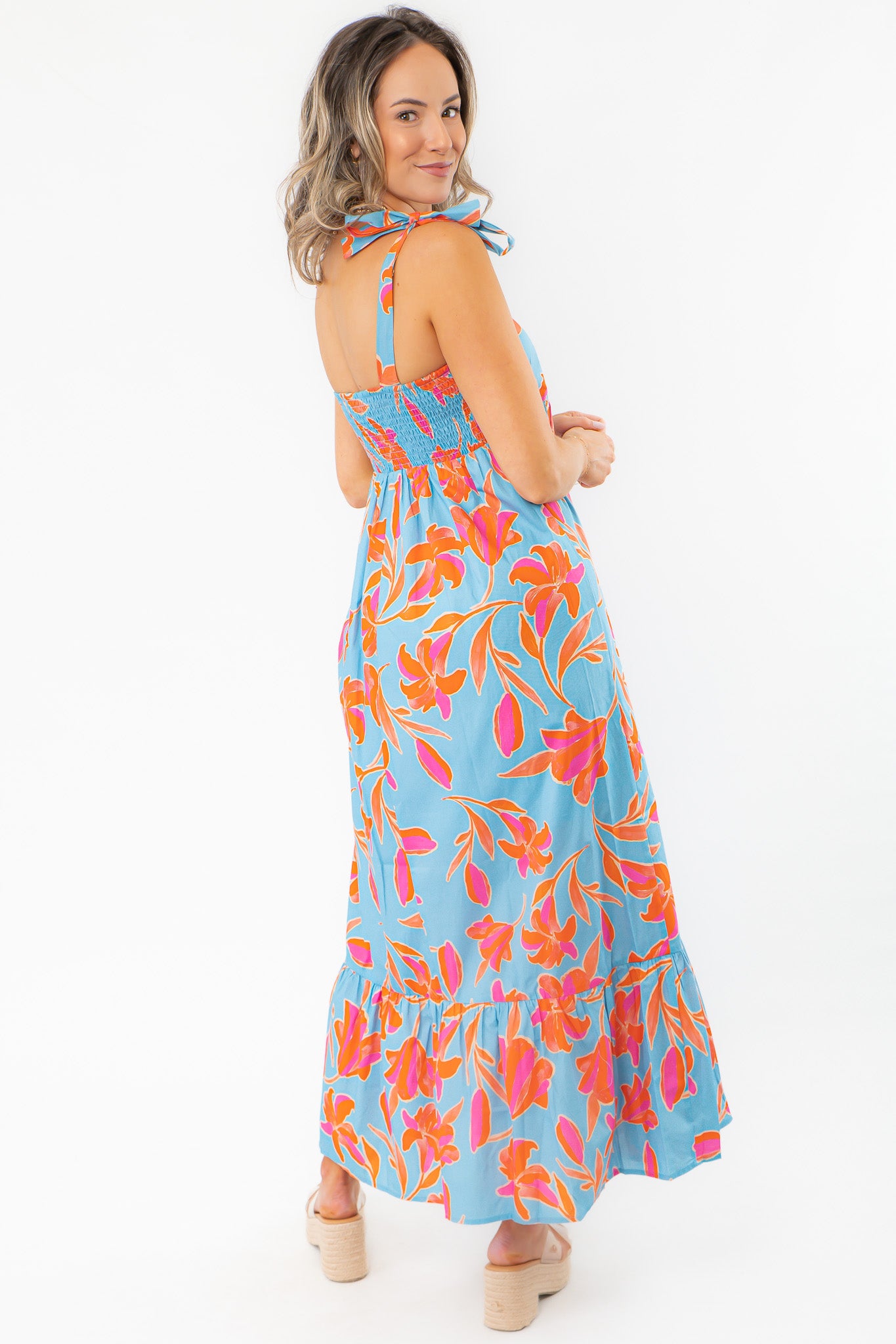 Back view of THML Tie Strap Flower Print Maxi Dress featuring smocked bodice and flowy skirt, designed for comfort and vacation style.