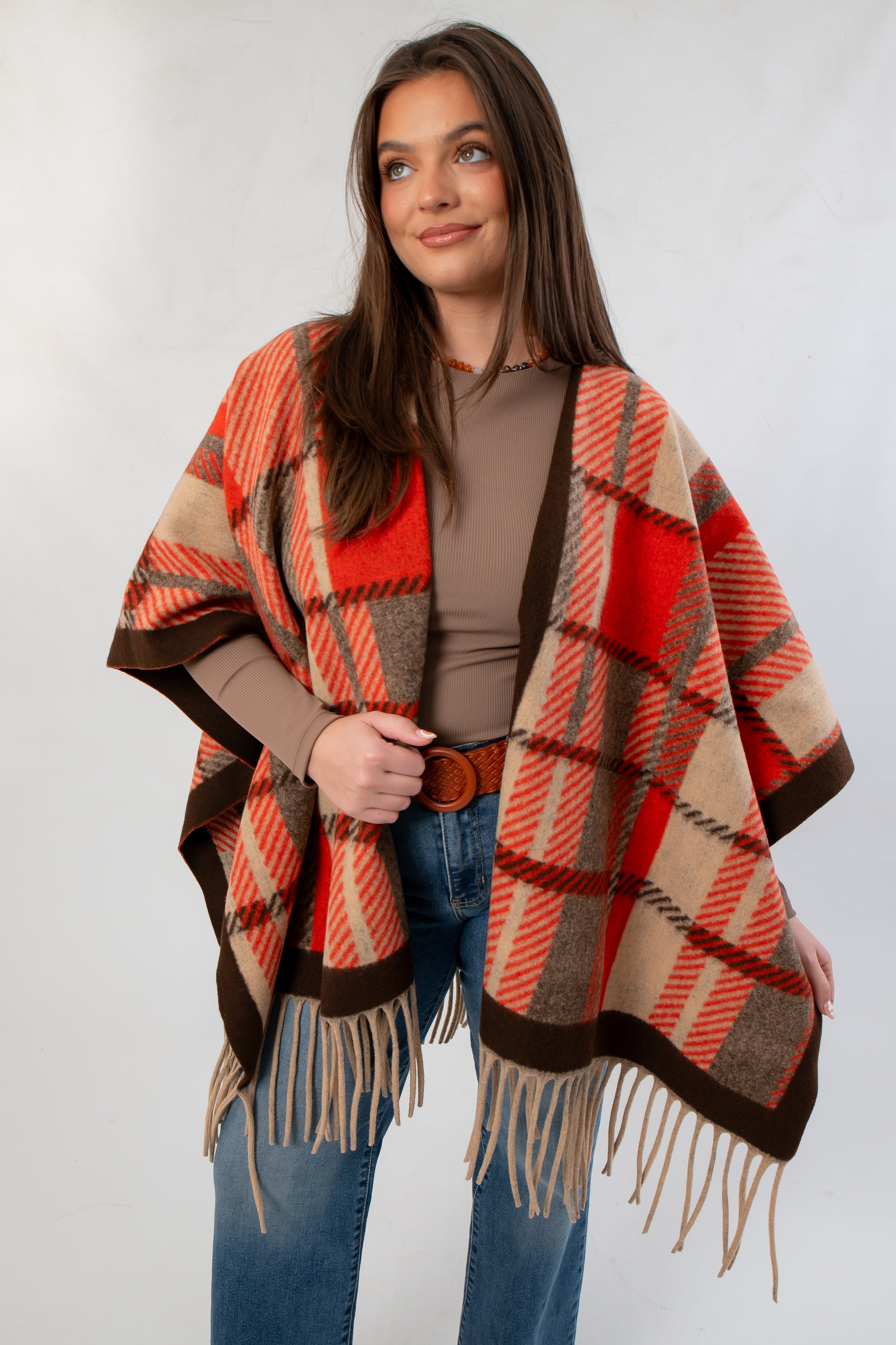 Fireside Plaid Shawl in cozy orange and brown tones with fringe detail, styled over a taupe top and jeans for fall fashion.