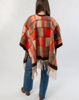 Back view of Fireside Plaid Shawl highlighting its bold orange plaid design and soft fringe, styled for autumn comfort and charm.