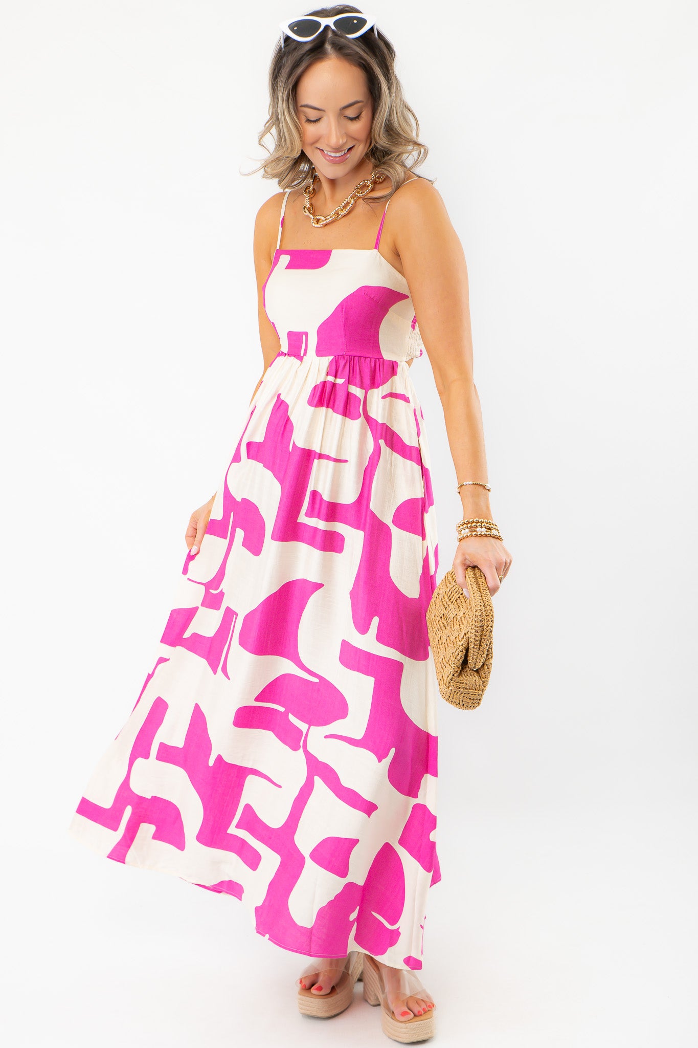 Model wearing Meet Me in Santorini Fuchsia Wave Maxi Dress with woven clutch, perfect for casual resort and beach outings.