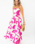 Model wearing Meet Me in Santorini Fuchsia Wave Maxi Dress with woven clutch, perfect for casual resort and beach outings.