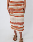 Close-up of knit midi skirt with sunset stripe design, beige and orange colors, summer fashion