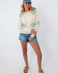 Model wearing coastal cream seashell knit sweater with denim shorts and cap