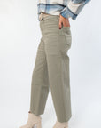 Side view of Rosemary Utility Wide Leg Jeans showing wide leg cut, cargo pocket detail, and raw hem in faded green denim.