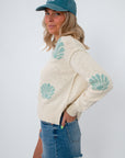 Back view of coastal cream seashell print knit sweater with beach-themed pattern