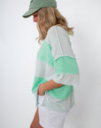 Back view of model in Seaglass Shine mint green oversized striped knit top with cap in apparel category