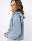 Side view of Ruffle-Trim Light Wash Denim Jacket showing soft ruffle detailing and relaxed fit, perfect for layering in spring fashion.