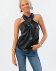 On Time Halter Neck Top - Black Faux Leather with crossover neckline and longline fit, styled with blue jeans for a chic casual look.