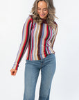 Steve Madden Burgundy Serra Stripe Sweater with multicolor vertical stripes and boat neck, styled with blue jeans for a cozy fall look.