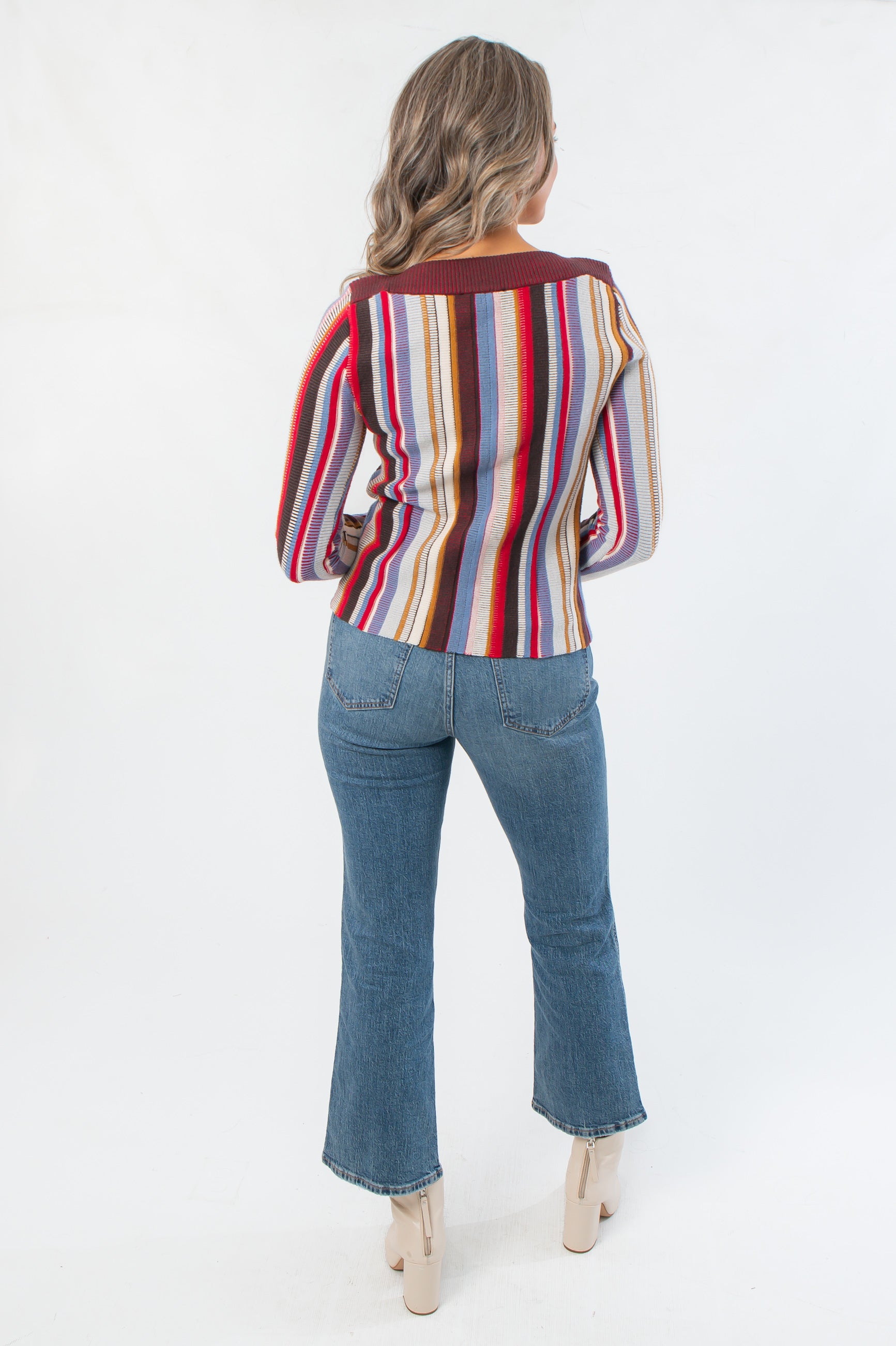 Back view of Steve Madden Burgundy Serra Stripe Sweater highlighting vertical stripe design and ribbed hem, styled with denim and heeled boots.