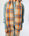 Close-up of Highland Plaid Skinny Scarf by Free People featuring soft texture and vibrant orange and blue plaid pattern, ideal for fall fashion.