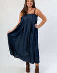 Denim Buckle Strap Dress by THML in midi length, featuring pleated design and adjustable brown straps, paired with heeled boots.