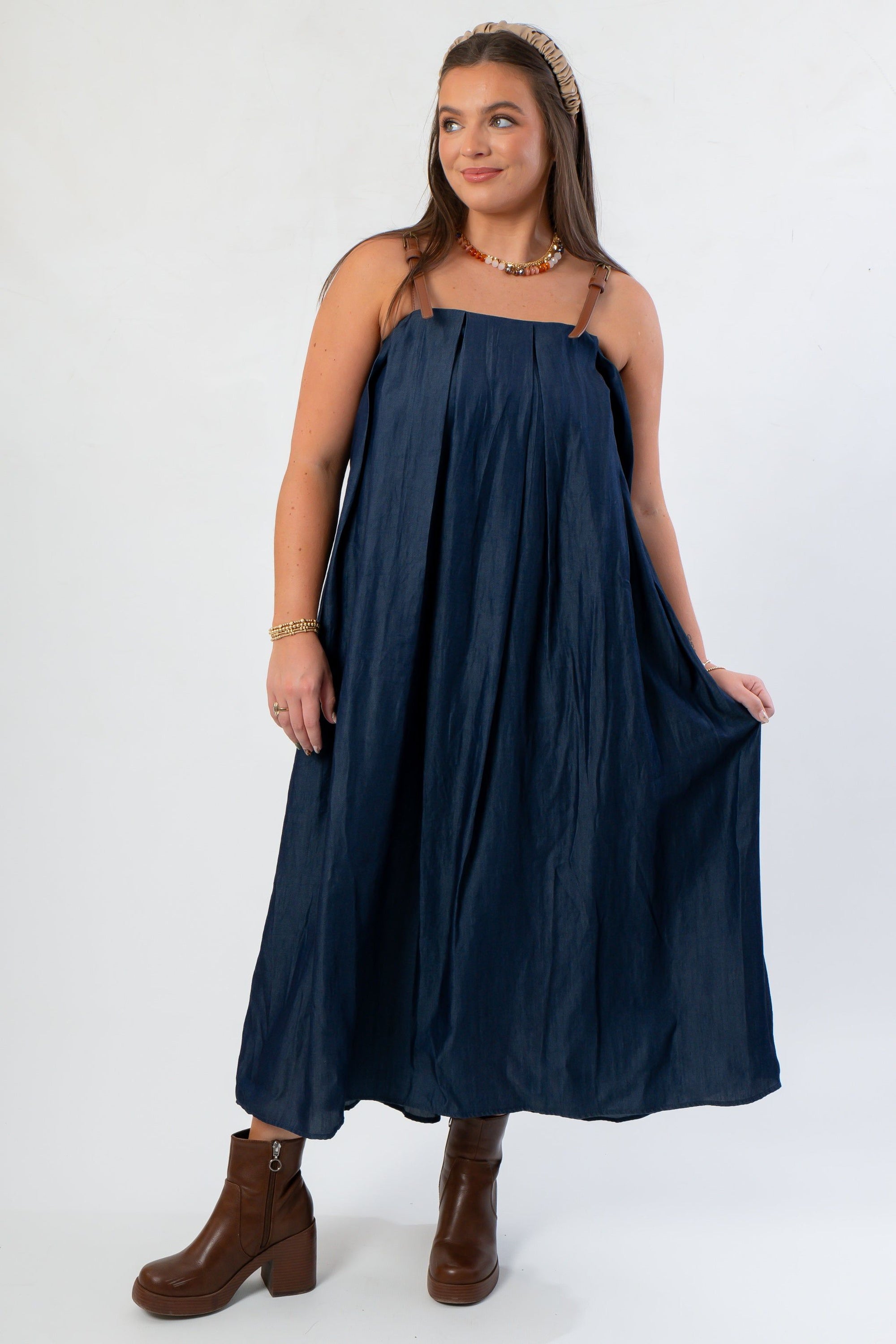 Front view of THML Denim Buckle Strap Midi Dress with relaxed fit and square neckline, styled with brown platform boots.