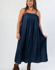 Front view of THML Denim Buckle Strap Midi Dress with relaxed fit and square neckline, styled with brown platform boots.