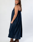 Side profile of THML Denim Buckle Strap Dress highlighting its flowy midi length and soft denim texture, perfect for fall fashion.