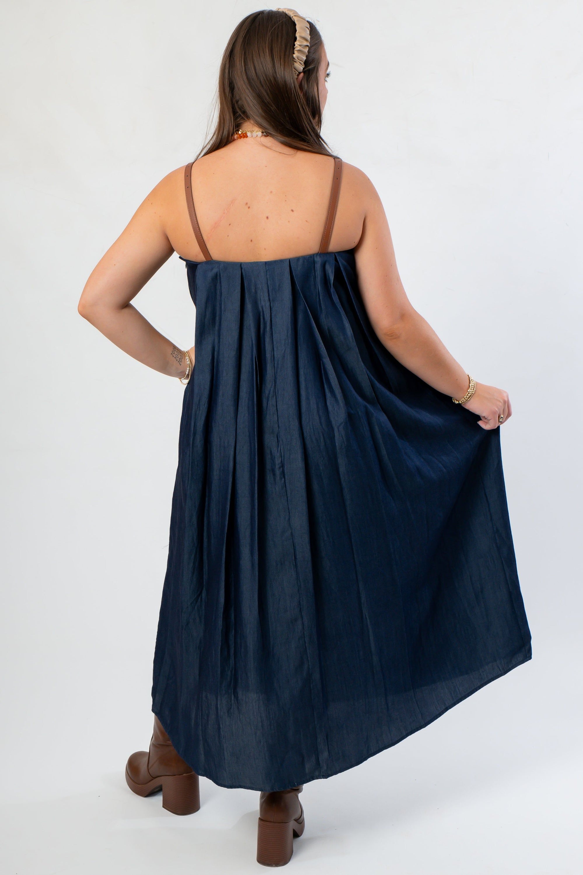 Back view of THML Denim Midi Dress showing pleated fabric and brown buckle straps, ideal for versatile seasonal styling.