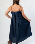 Back view of THML Denim Midi Dress showing pleated fabric and brown buckle straps, ideal for versatile seasonal styling.