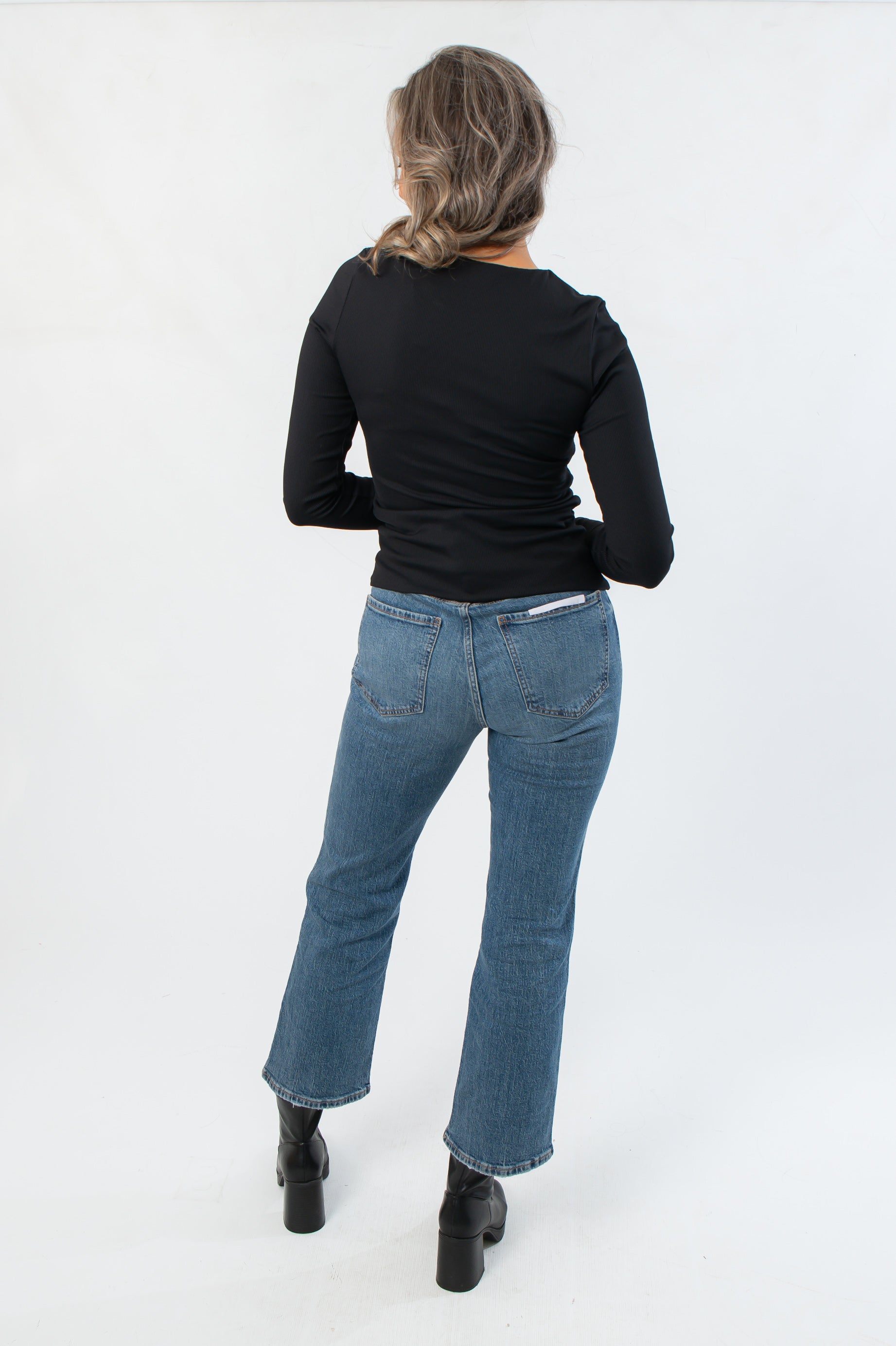 Back view of Roxi Jet Black Ribbed Knit Top paired with denim, highlighting its smooth ribbed texture and flattering slim fit.