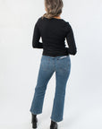 Back view of Roxi Jet Black Ribbed Knit Top paired with denim, highlighting its smooth ribbed texture and flattering slim fit.