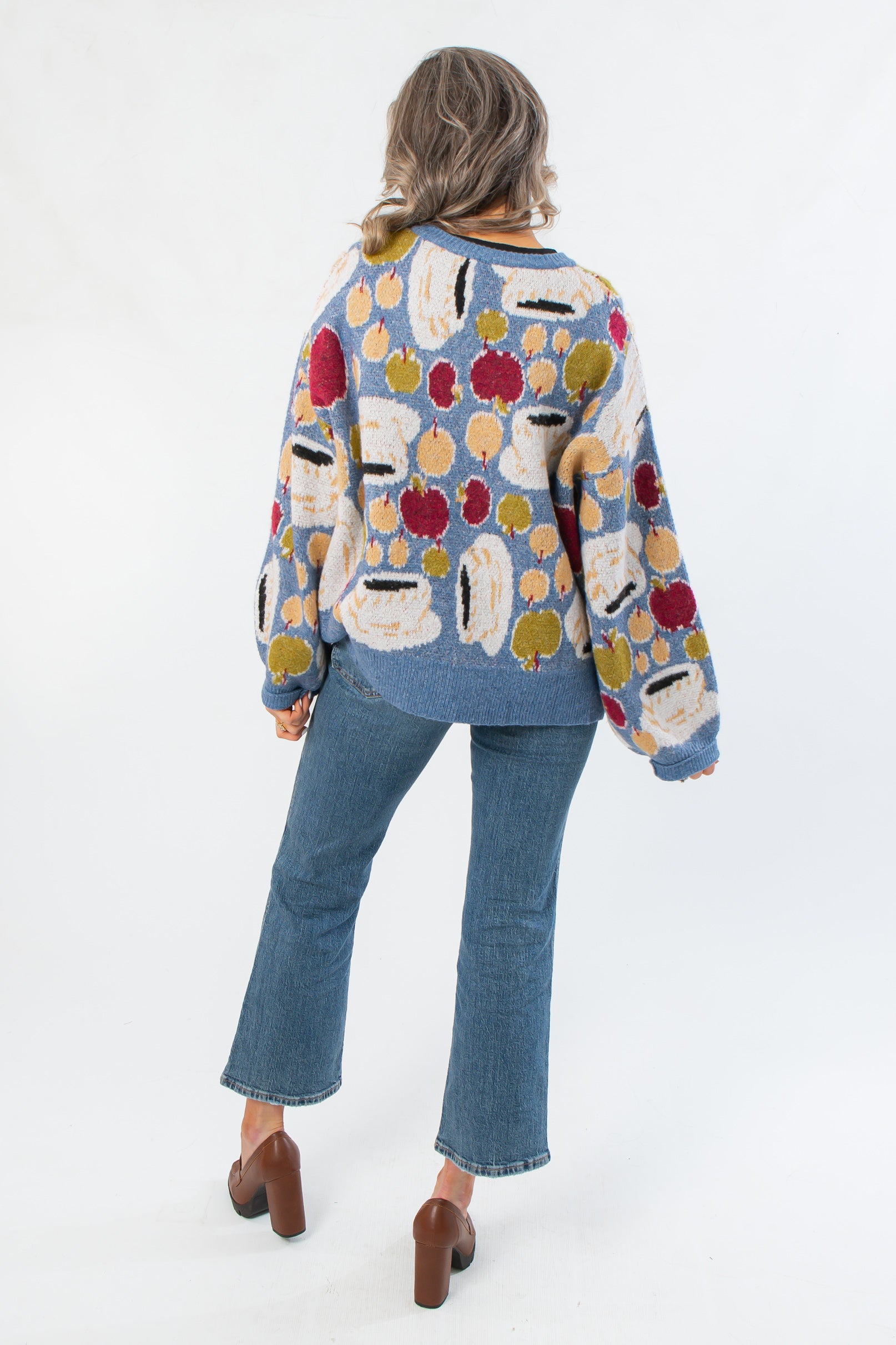 Back view of Apple A Day Blue Tie Front Cardigan showcasing multicolor apple knit design and oversized silhouette in soft blue fabric.