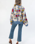 Back view of Apple A Day Blue Tie Front Cardigan showcasing multicolor apple knit design and oversized silhouette in soft blue fabric.