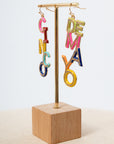 Colorful letter earrings on display stand