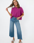 Model wearing Whatever The Weather Orchid Sleeveless Sweater paired with wide-leg jeans and sandals. Stylish purple knit top for casual everyday wear.