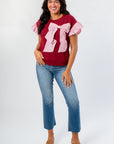 Burgundy Bow Cable Knit Top with pink ruffle sleeves and oversized bow, styled with cropped jeans and wedge sandals for a cozy chic look.
